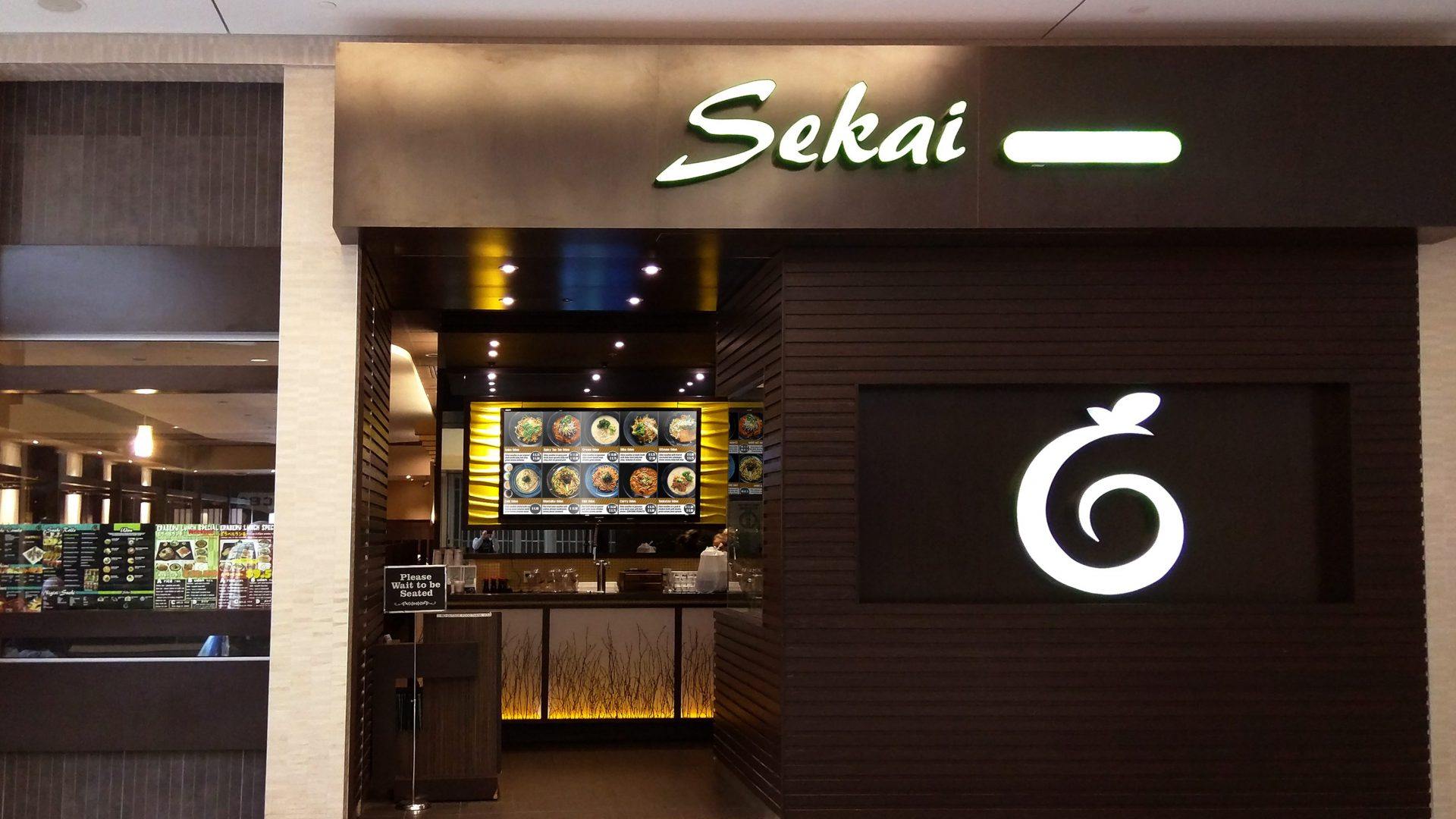 Front of Sekai Udon, a restaurant, with a digital menu board hanging above the counter