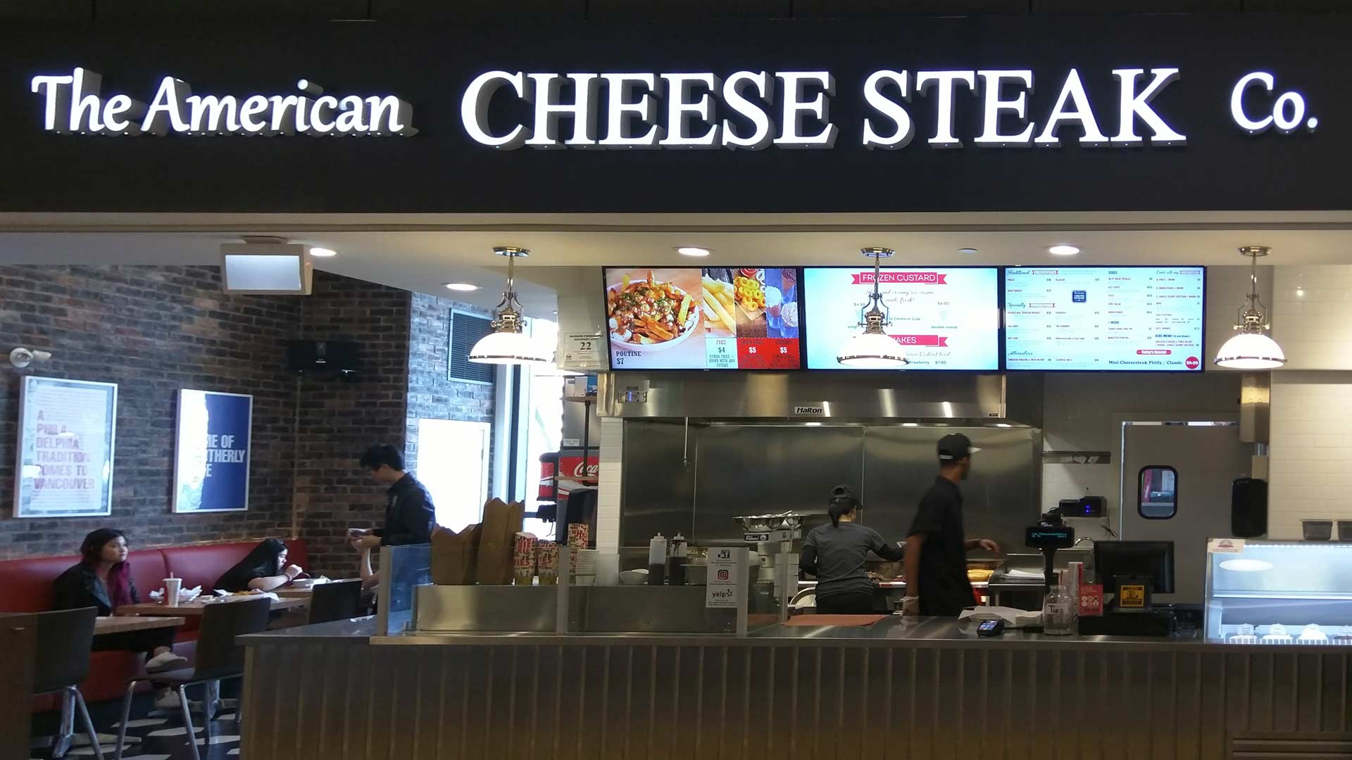 Front of the American Cheese Steak Co quick service restraurant with digital menu board mounted above the counter