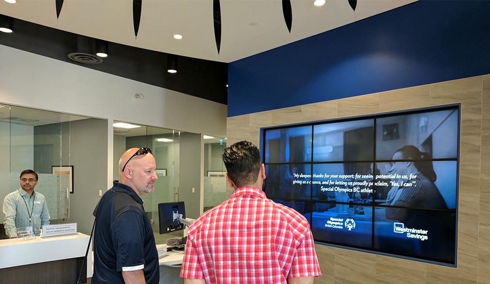 Two men looking at the newly installed video wall at a Westminster Savings Credit Union branch