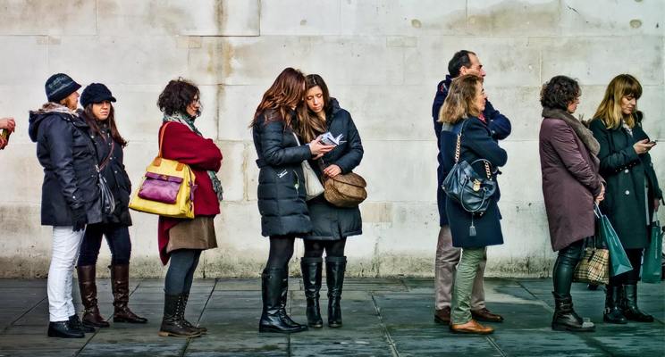 Individuals standing in line outside wearing jackets