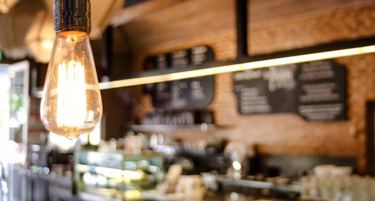 Old fashioned light bulb in foreground with cafe in background