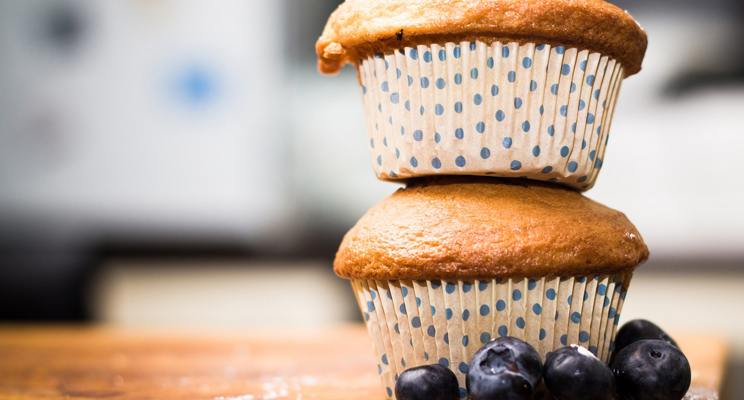 Two stacked muffins with blueberries around the base on top of a table