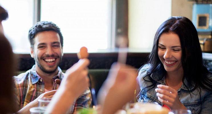 Smiling couple enjoying a meal at a restaurant with their friends