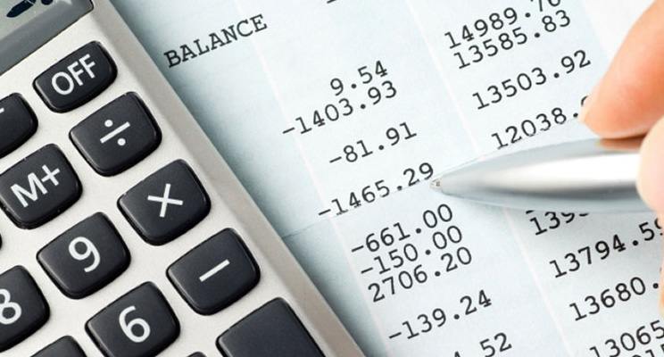 Close view of a balance sheet with a calculator and pen on top of it