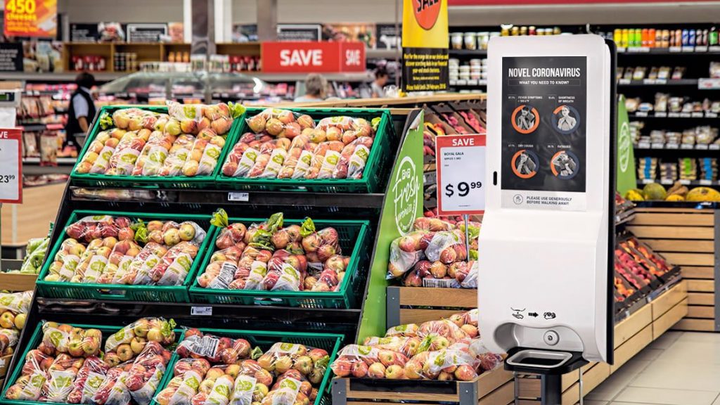 digital hand sanitizer kiosk, in supermarket, next to fruit
