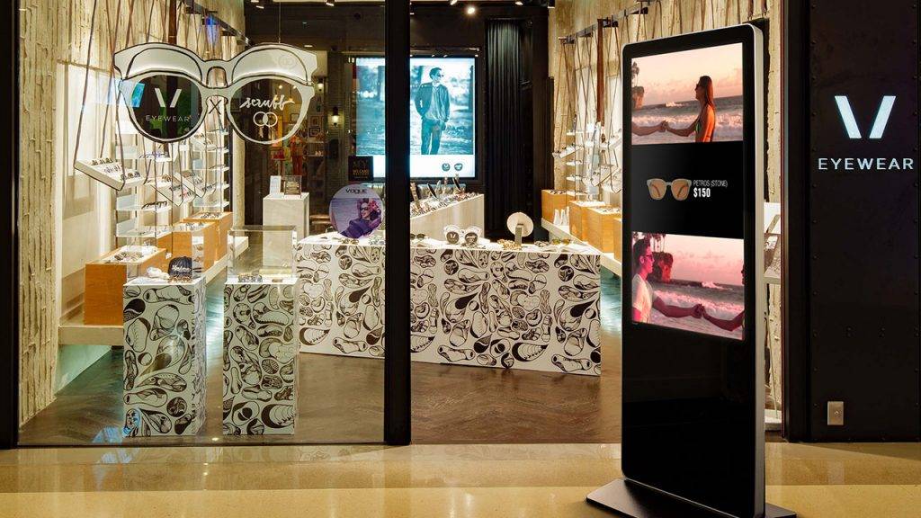 Digital signage kiosk display showing a design for a sale on frames in front of a trendy eyewear store